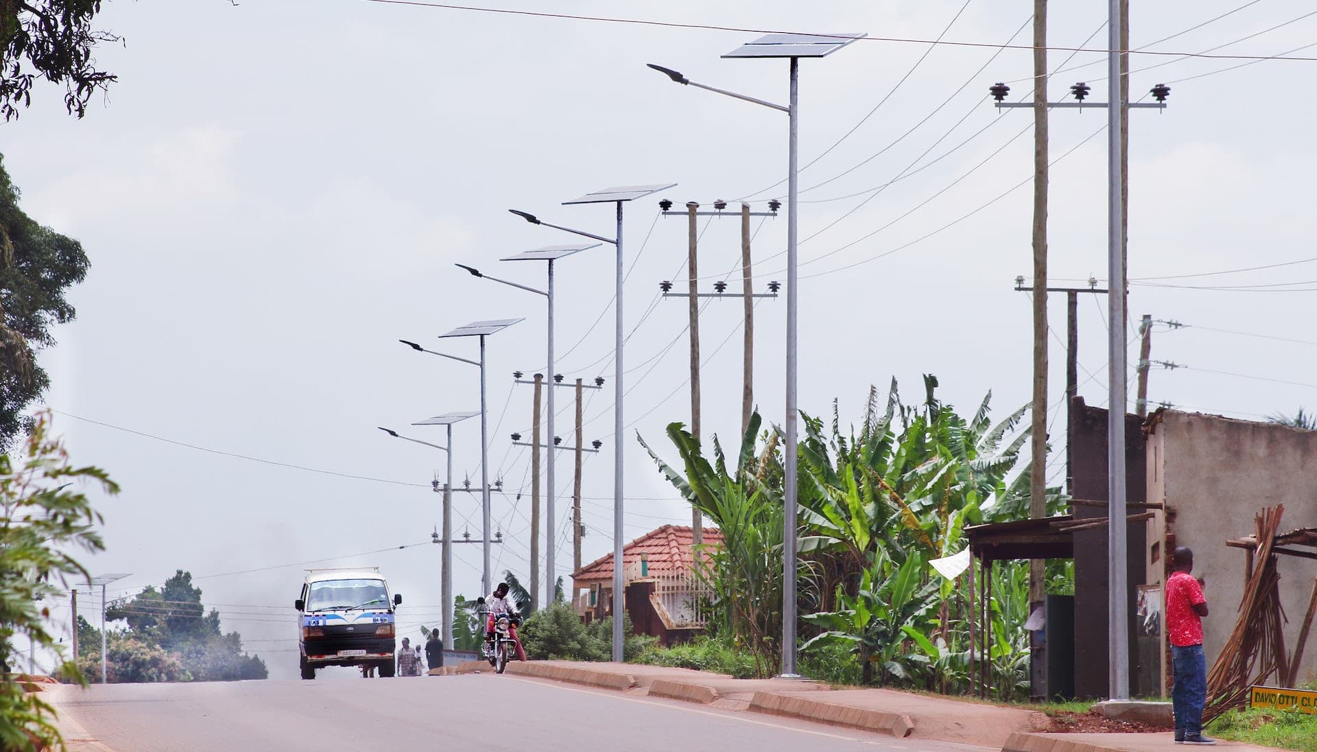 A road where a series of utility poles with solar panels are mounted.